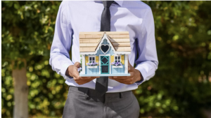 Realtor Holding a Miniature House